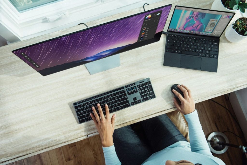 a person working at an organized clutter free desk with laptop and computer monitor